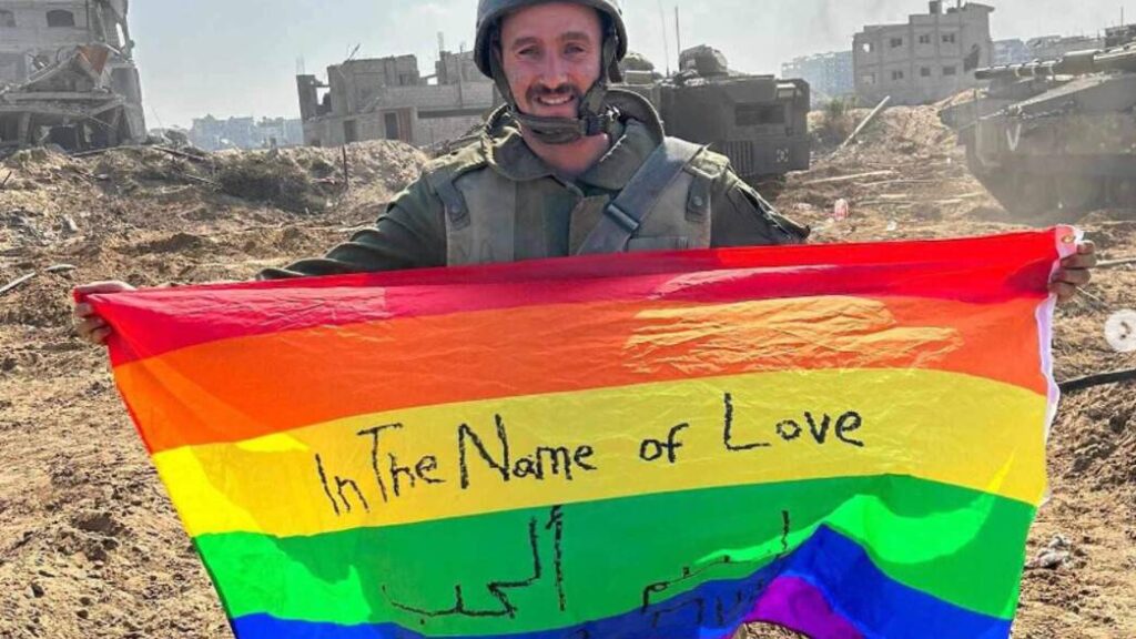 A soldier holding an LGBT flag over the ruins of Gaza.